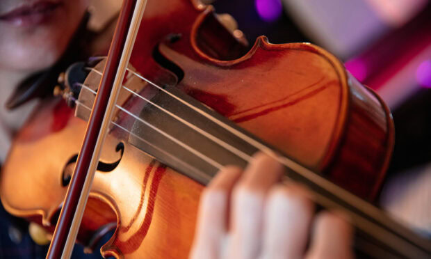 Close up view of a viola being played showcasing the wood grain and strings