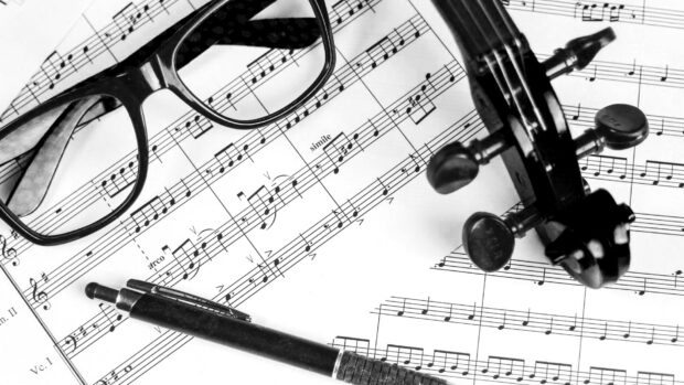 Black and white sheet music with a viola and glasses on a music score
