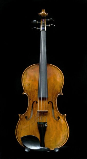 A vintage wooden viola with fine craftsmanship displayed on a black background