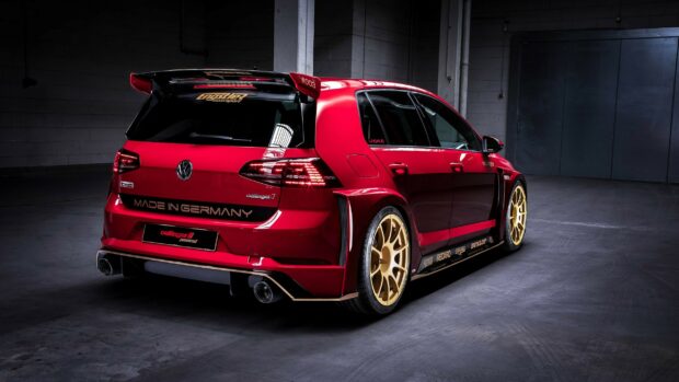 Red Volkswagen car with custom gold wheels in a dark garage setting