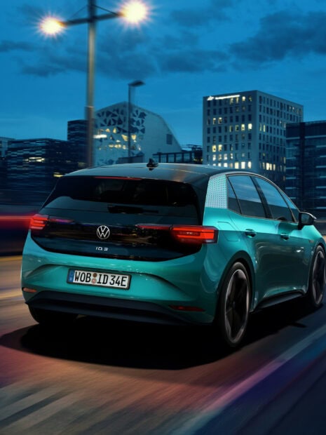 Volkswagen electric car driving through a city at night with illuminated buildings and streetlights
