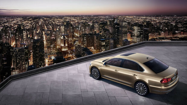 A golden Volkswagen sedan parked on a rooftop overlooking a city skyline at dusk