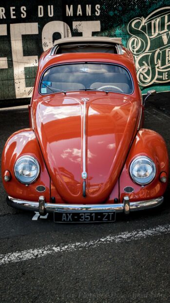 Classic Volkswagen car parked in front of a vintage styled mural at a street location