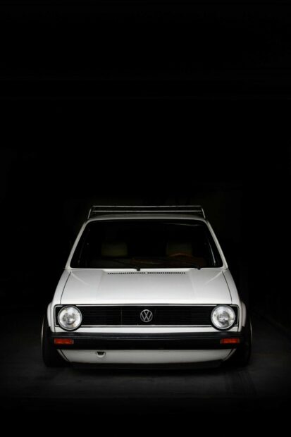 White Volkswagen car front view in a dark garage showcasing classic Volkswagen design