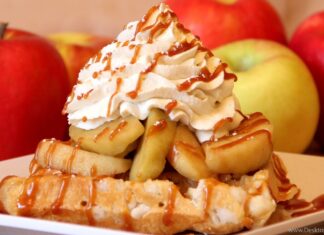 A delicious waffle topped with caramel and apples with whipped cream on a plate