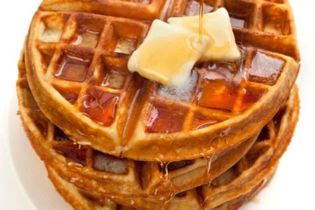 Close up of waffle with butter and syrup drizzling on top