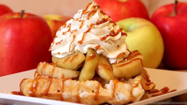 A delicious waffle topped with caramel and apples with whipped cream on a plate