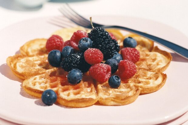 A heart shaped waffle topped with fresh raspberries blackberries and blueberries