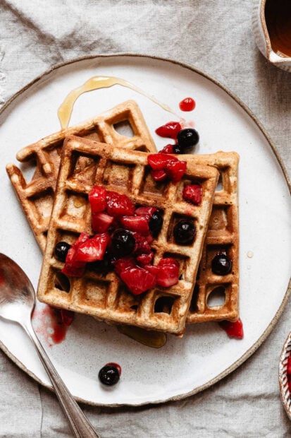 Fresh waffle with mixed berry topping and syrup on a plate