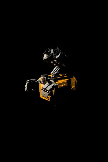 Lego robot inspired by Walle character in dark background with glowing eyes