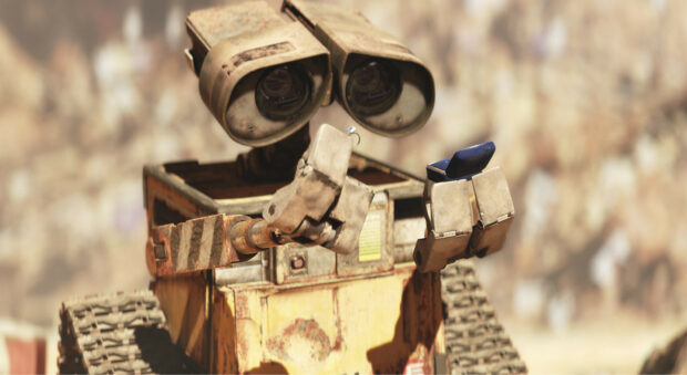 Rusty robot holding a small object in a stadium crowd scene