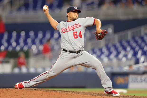A Washington Nationals pitcher in full motion delivering a pitch during a baseball game