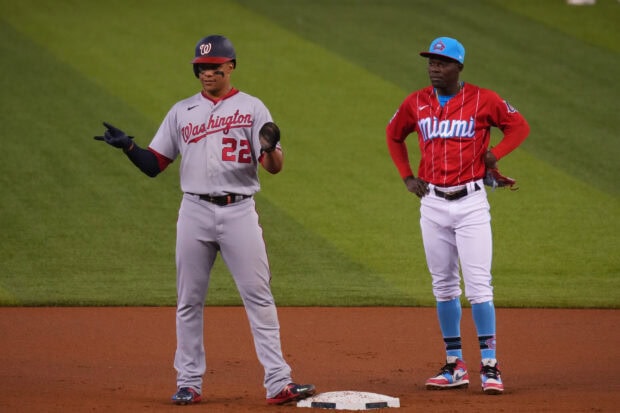 A Washington Nationals player standing on the base during a baseball game against a Miami team player on the field