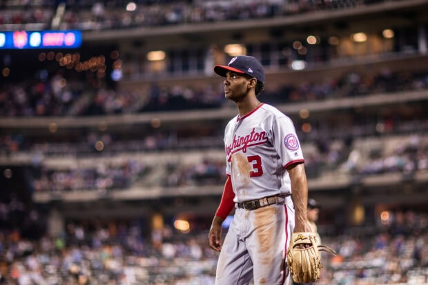 A Washington Nationals player stands on the field during a baseball game in a stadium filled with spectators