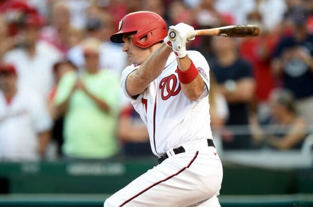 A Washington Nationals player swinging a bat during a baseball game in front of a crowd