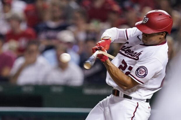 A Washington Nationals player hitting a baseball during a game in a full uniform