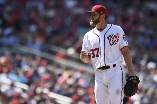 A Washington Nationals player preparing to pitch during a baseball game in a packed stadium