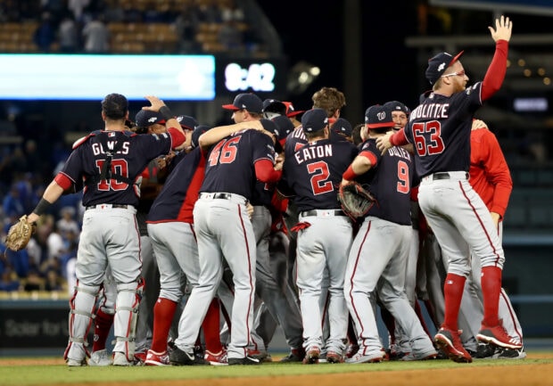 Washington Nationals players celebrating on the field in a group hug after a game win