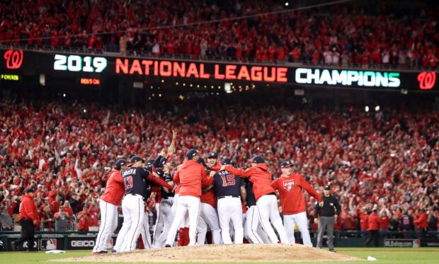 Washington Nationals team celebrating on pitcher's mound after winning National League Championship in front of cheering crowd