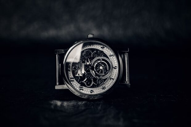 Mechanical watch showing detailed gears and dials on a dark surface
