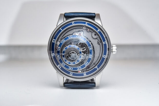 Mechanical watch with blue spiral dial and visible gears on a white background