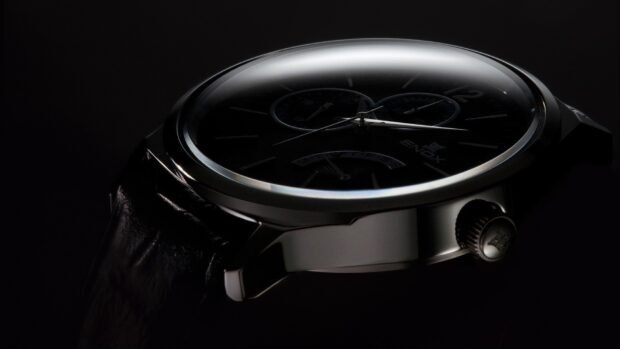 Close up of a luxury watch displaying time with a black leather strap