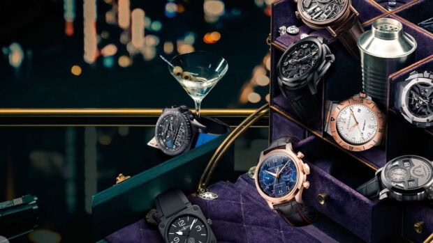 Luxury collection of watches displayed in a box with a martini glass in a stylish setting