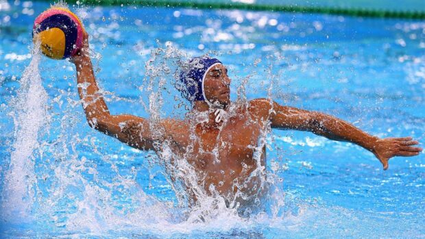 Male water polo player preparing to throw the ball during a match in the pool
