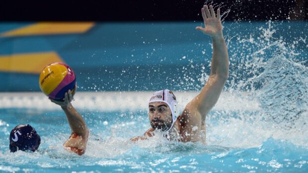Water polo players competing in a high intensity match with one player preparing to throw the ball