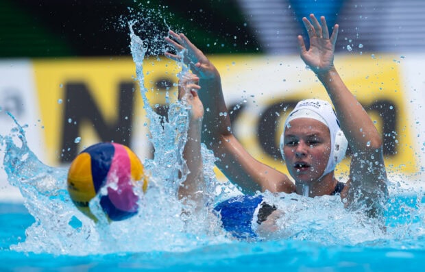 Female water polo player defending against opponent in water polo match