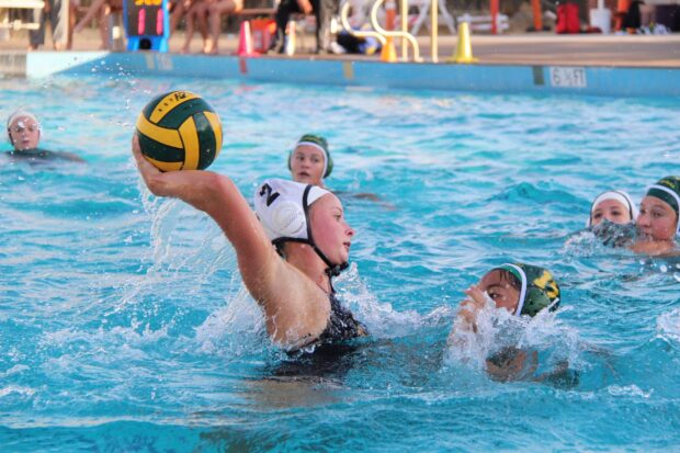 Female water polo player preparing to throw the ball during the match in the pool