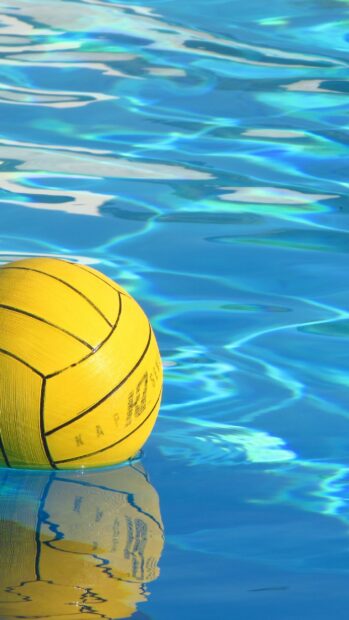 Yellow water polo ball floating on clear blue water surface in a pool