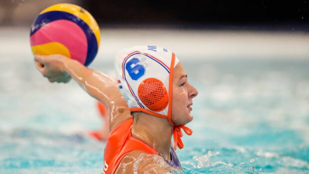 Female water polo player preparing to throw the ball in a competitive match in the pool