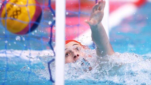 Water polo goalkeeper reaching to block the ball in a high action moment