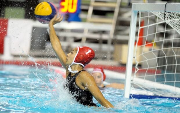 Female water polo player reaching for the ball during a match in a swimming pool