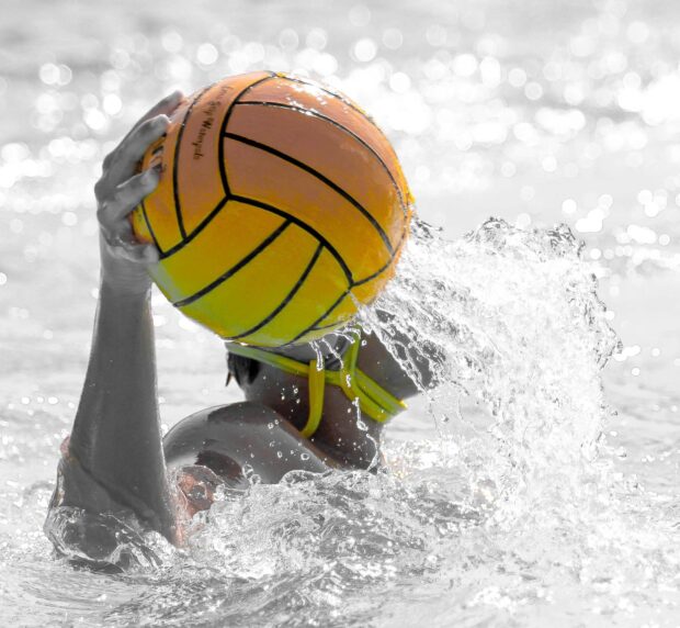 Water polo player preparing to throw the ball during an intense match in the pool