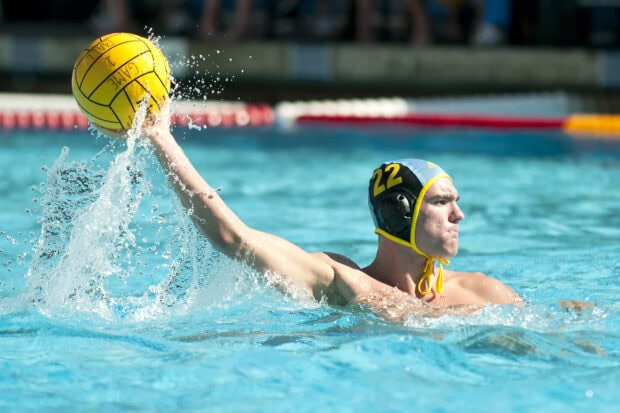 Water polo player wearing cap number 22 preparing to throw the ball in the pool