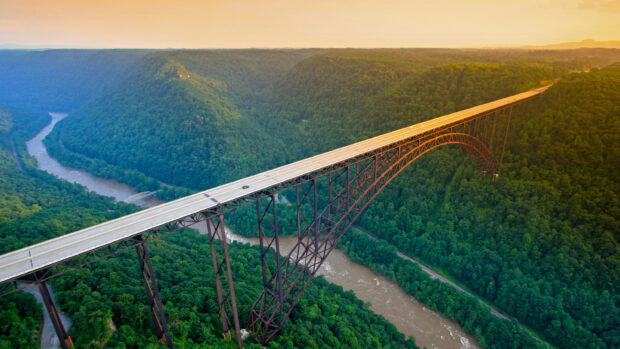A steel arch bridge crossing a river surrounded by lush green hills in West Virginia