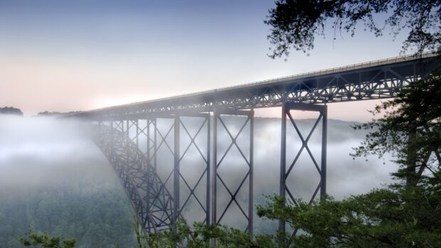 A steel bridge in West Virginia surrounded by fog and lush green forest
