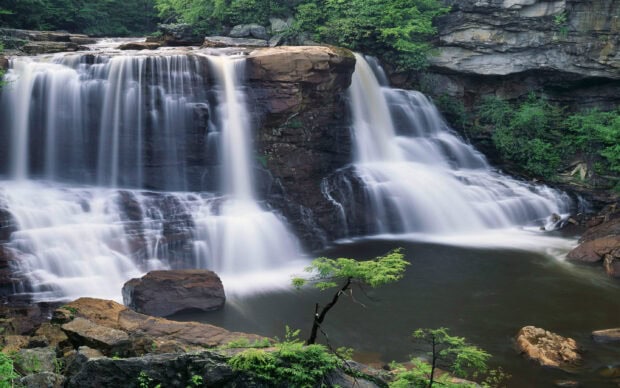 A calm river flows over rocks in a scenic West Virginia nature setting