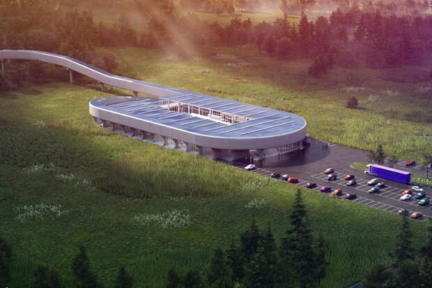 A modern building in West Virginia surrounded by green fields and a parking lot filled with cars