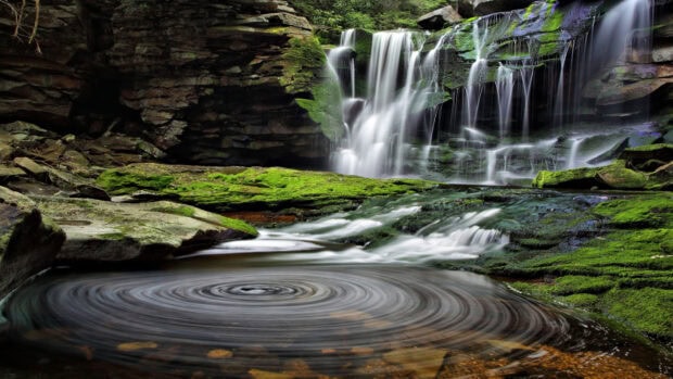 A waterfall surrounded by lush green moss and rocks in West Virginia forest
