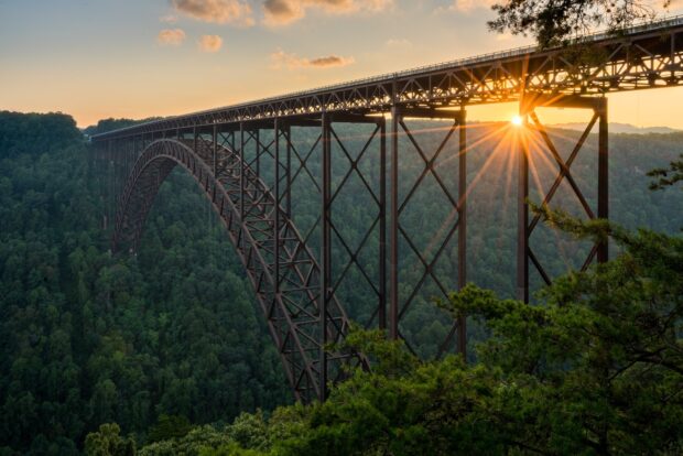 Stunning West Virginia bridge surrounded by forest at sunset with sun rays