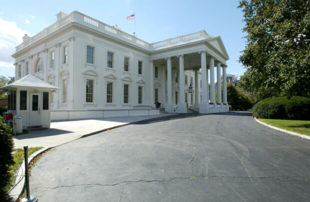 The White House building with American flag and surrounding greenery in clear daylight
