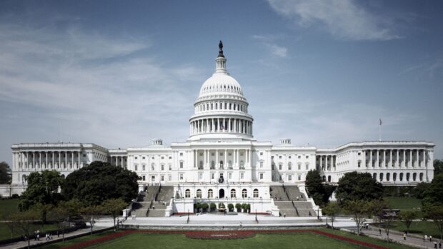 The United States Capitol building under a clear sky with green lawns in front