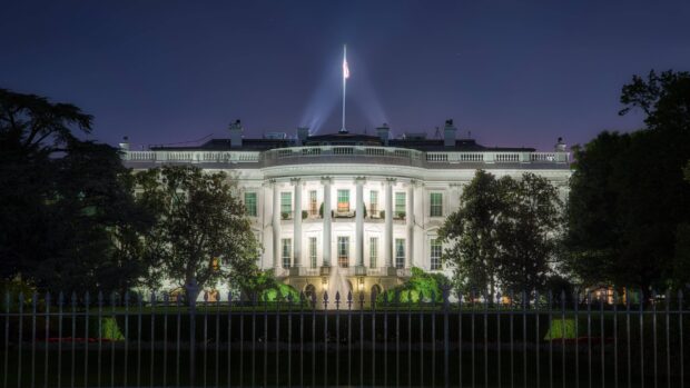 The White House lit up at night with a clear sky and surrounding trees in Washington DC