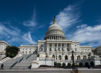 The White House stands against a bright blue sky with scattered white clouds