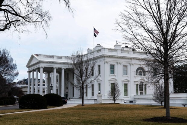 The White House building with flags and bare trees in the winter landscape