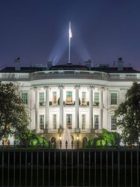 Night view of the White House with the flag illuminated and fountain in front
