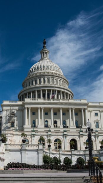 The White House dome with American flag under a clear blue sky